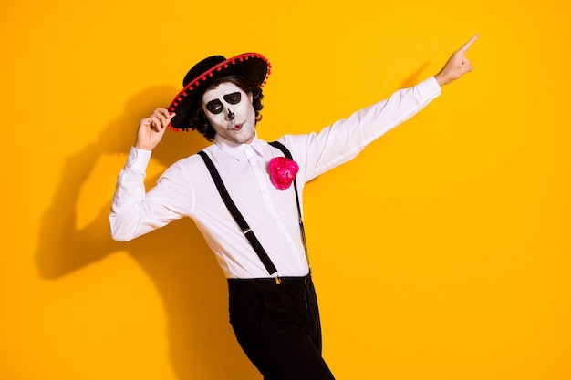 Foto del profilo di ragazzo carismatico spaventoso tradizione spagnola danza tenere berretto diretto dito spazio vuoto indossare camicia bianca rosa morte costume sombrero bretelle isolate colore giallo sfondo