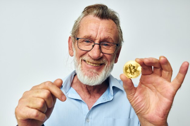 Foto del vecchio pensionato finanza monete d'oro bitcoin in posa sfondo isolato