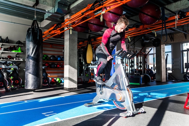 Foto dell'atleta è impegnato su un'attrezzatura cardiovascolare in un centro fitness con tempo soleggiato.