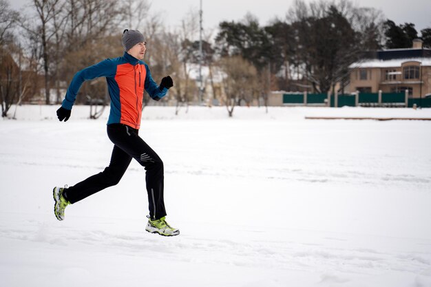 Foto dell'atleta in esecuzione tra gli alberi nella foresta invernale