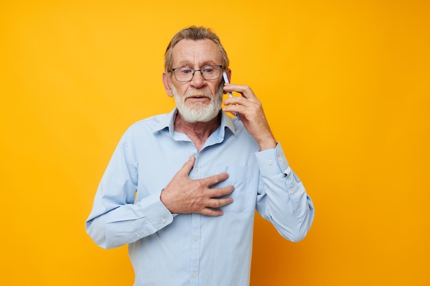 Foto della barba grigia del vecchio pensionato con gli occhiali che parlano sullo sfondo giallo del telefono