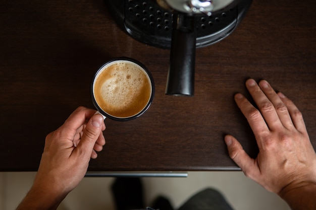 Foto della caffettiera, mani dell'uomo che versa il caffè in tazza in cucina