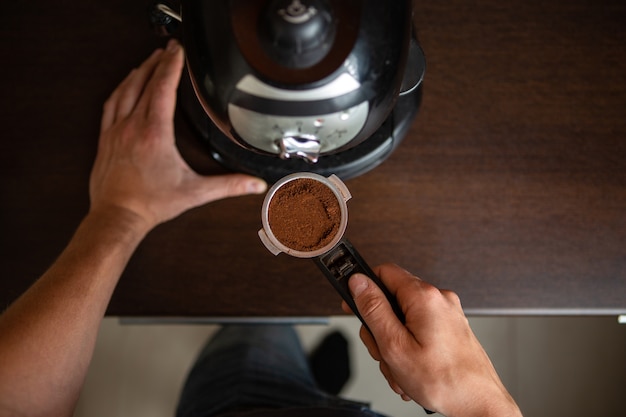 Foto della macchina per il caffè, mano dell'uomo che versa il caffè in cucina