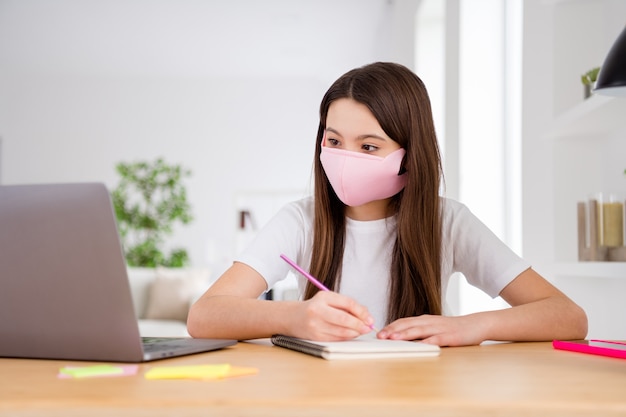 foto della piccola allieva signora laptop tavolo lezione online scrivere note indossare maschera