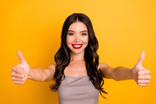 Foto della ragazza carina carina positiva allegra che sorride a trentadue denti esprimendo emozioni positive sul viso che mostra due pollici su sfondo di colore vivido isolato