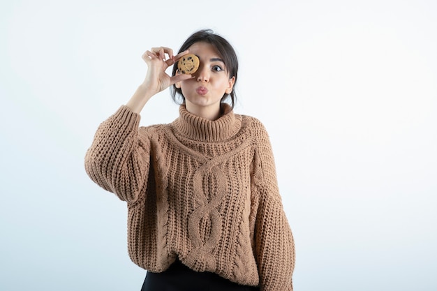 Foto della ragazza che nasconde gli occhi dietro i biscotti su priorità bassa bianca.