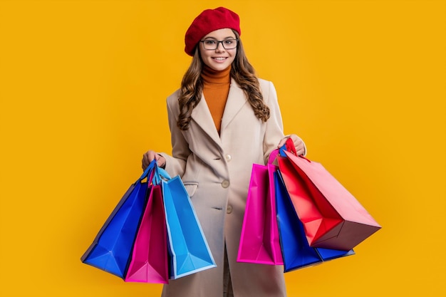 Foto della ragazza teenager alla moda felice con le borse della spesa La ragazza teenager tiene le borse della spesa