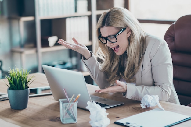 Foto della signora di affari che guarda netbook che guarda problemi di grido dello schermo