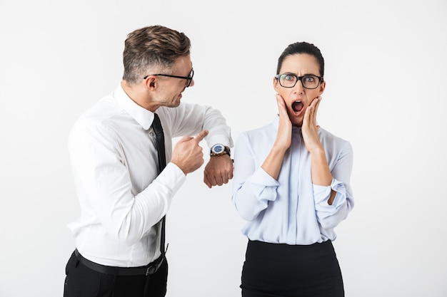 Foto delle coppie arrabbiate dispiaciute dei colleghi di lavoro di litigio isolate sopra l'orologio di rappresentazione della parete bianca.