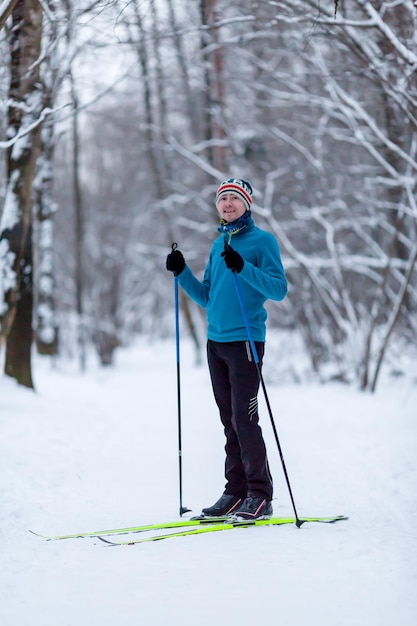 Foto dello sciatore maschio in giacca blu nella foresta invernale