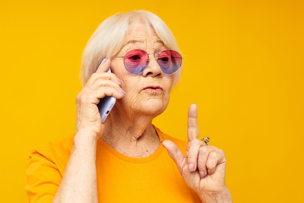 Foto dello stile di vita felice della vecchia signora in pensione in magliette gialle con le emozioni del primo piano del telefono