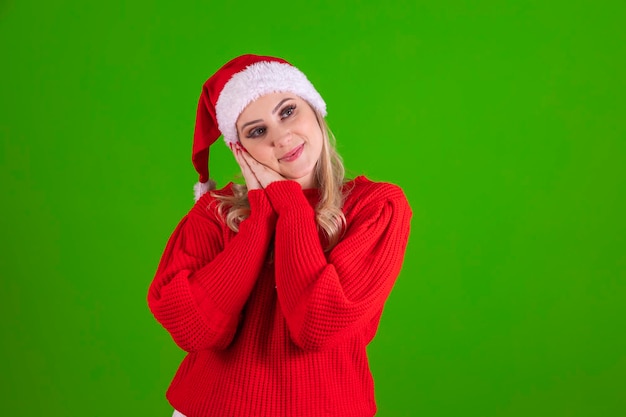 Foto di affascinante donna sorridente sognante che si tiene per mano guancia dormendo sognando ad occhi aperti isolato su sfondo di colore verde con abito natalizio