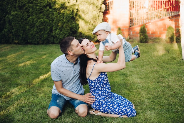 Foto di allegra mamma caucasica, papà e il loro bambino si divertono insieme e sorridono in giardino