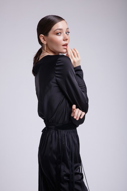 Foto di alta moda di donna elegante con accessori per pantaloni con frange di camicetta nera su sfondo grigio