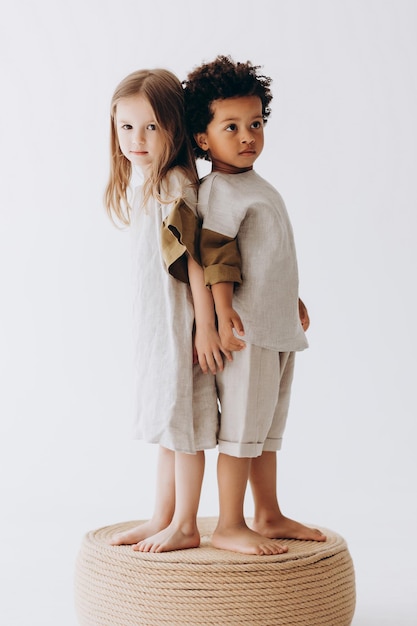 Foto di bambini che si divertono e posano per una foto in abiti di lino estivi in uno studio fotografico Ragazzo dalla pelle scura e ragazza caucasica insieme nella foto
