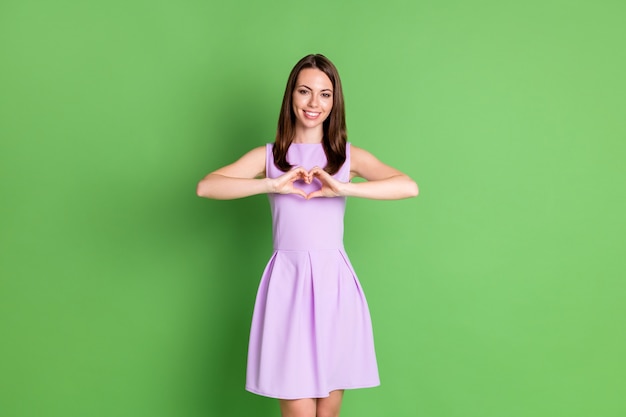 Foto di bella bella ragazza signora sorriso a trentadue denti mostra cuore forma due mani guardano macchina fotografica dimostrare sentimenti di amore gentilezza vestiti vestiti viola isolato sfondo di colore verde pastello