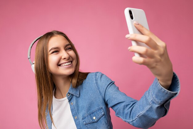 Foto di bella giovane donna bionda sorridente felice che indossa camicia di jeans blu e maglietta bianca