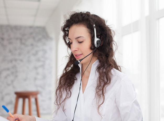 Foto di bella giovane operatore di call center in piedi su sfondo bianco