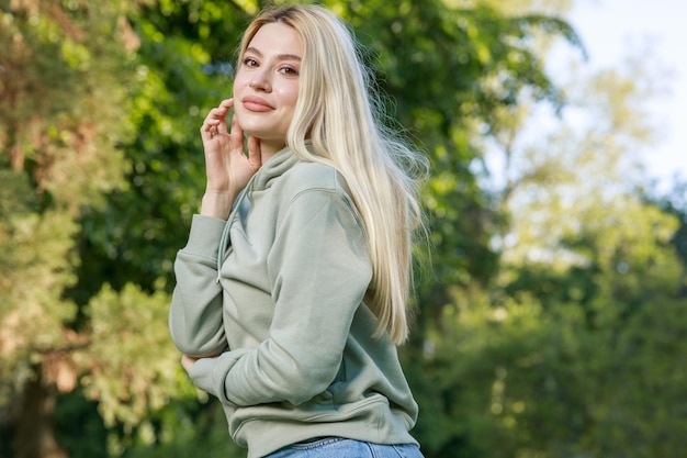 Foto di bella ragazza in piedi al parco e guardando la telecamera