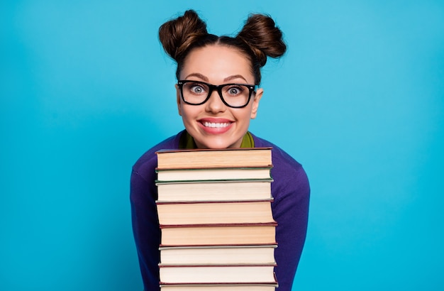 Foto di bella studentessa signora due panini divertenti appoggiati testa mento libri pila diligente allievo visita biblioteca appassionato di lettura indossare camicia pullover specifiche isolato colore blu sfondo