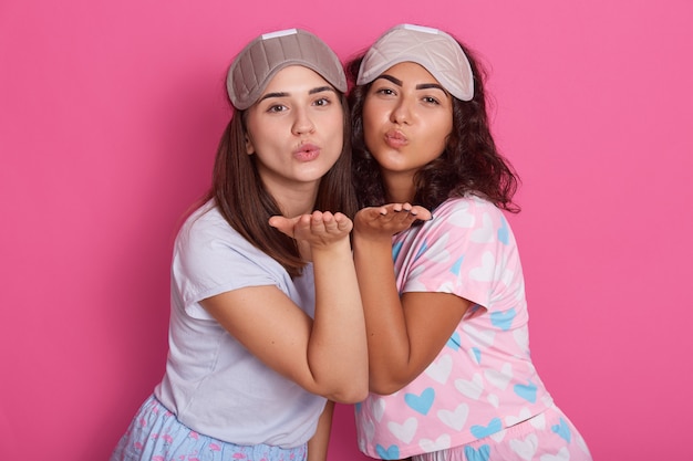 Foto di belle ragazze che posano in pigiama. Lo studio ha sparato di due amici che stanno sul rosa