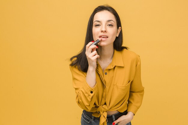 Foto di concetto di donna carina fare il trucco e tiene il rossetto