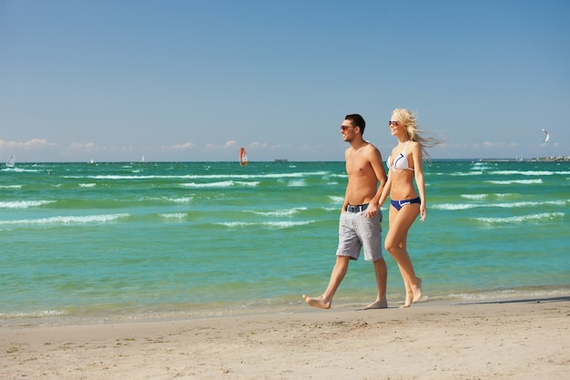 foto di coppia felice che cammina sulla spiaggia.