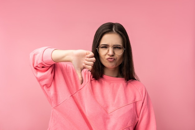 Foto di donna attraente con gli occhiali delusa, in disaccordo e antipatia per qualcosa