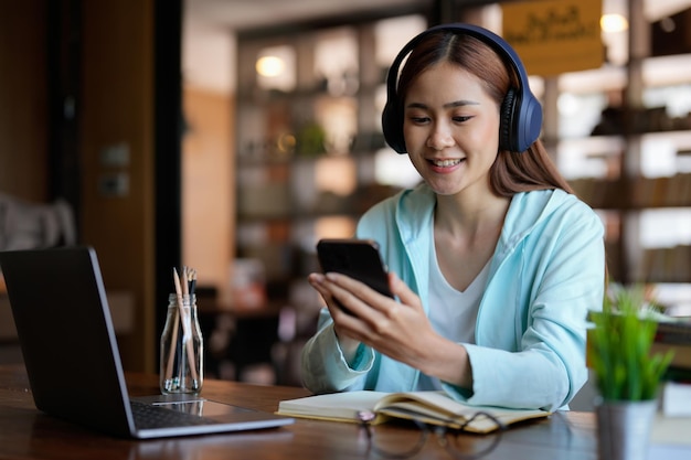 Foto di donna che indossa le cuffie e utilizza il telefono cellulare per il corso educativo di apprendimento online o il concetto online di formazione per seminari di formazione