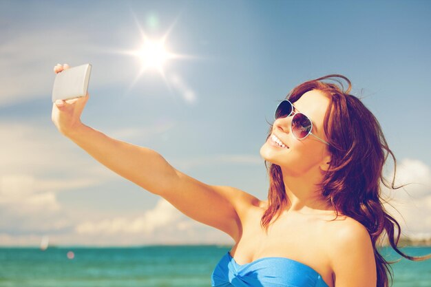 foto di donna felice con il telefono sulla spiaggia.