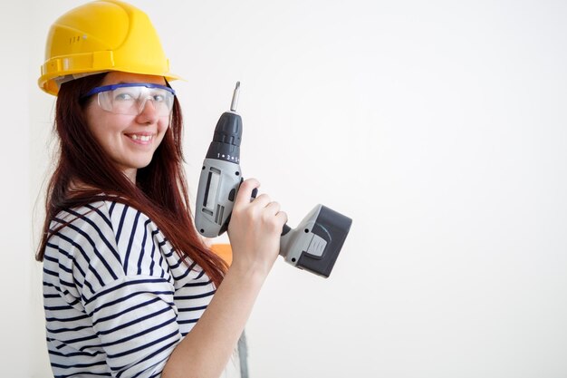 Foto di donna in casco giallo con trapano in mano appartamento