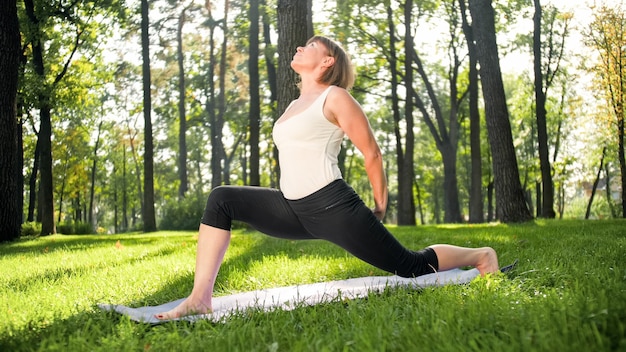 Foto di donna sorridente di mezza età che pratica asana di yoga. Persona che medita nella natura. Equilibrio e armonia di corpo e mente