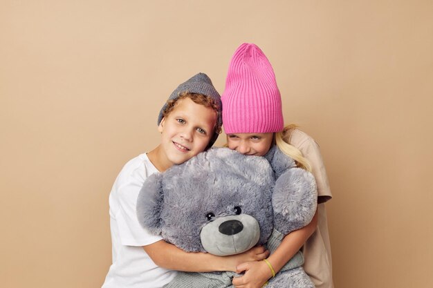 Foto di due bambini con cappello e amicizia con un orsacchiotto. Stile di vita inalterato