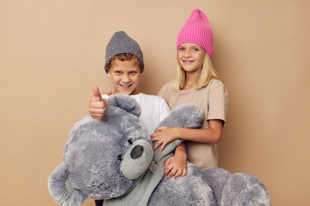 Foto di due bambini in intrattenimento con cappelli multicolori in posa su sfondo beige