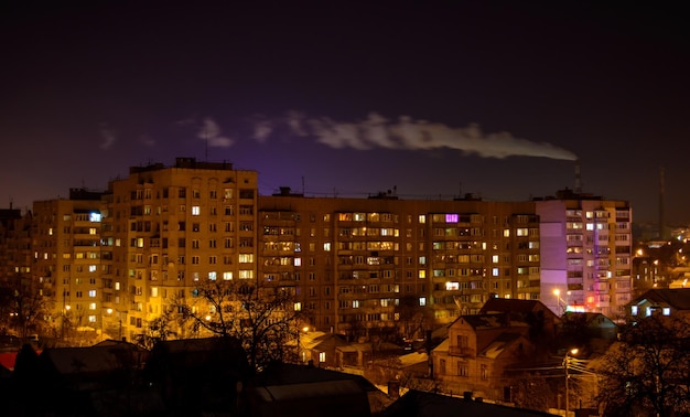 Foto di edifici della città di notte con fumo di fabbrica sopra di loro