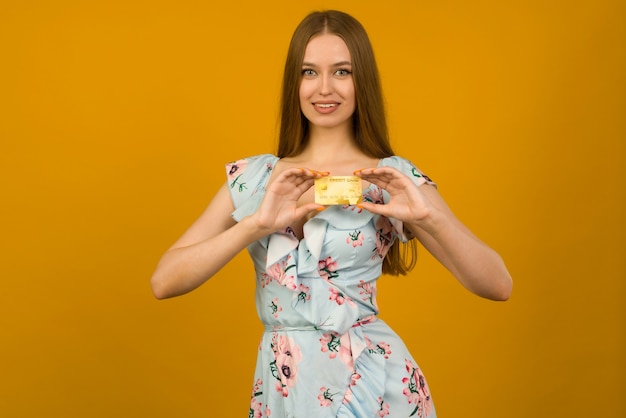 Foto di felice giovane donna in posa isolato su sfondo giallo muro tenendo la carta di debito o di credito.