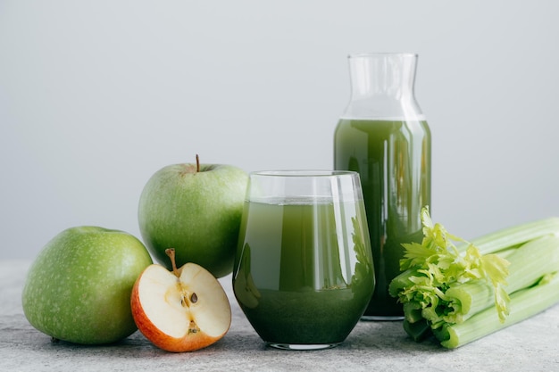 Foto di frullato verde con cerely e mela in due contenitori di vetro su sfondo bianco Succo biologico sano Concetto di dieta