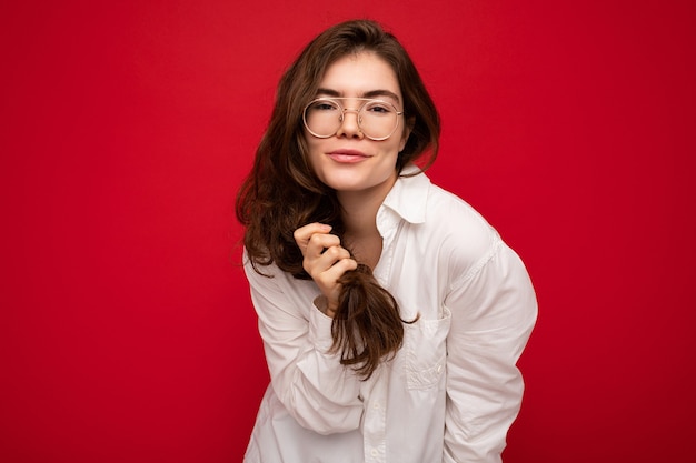 Foto di giovane bella donna castana felice che indossa camicia bianca e occhiali ottici sexy spensierata