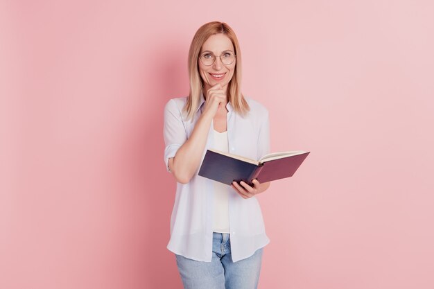 Foto di giovane donna attraente mano tocco mento felice sorriso positivo leggere la storia del libro isolato su sfondo color pastello