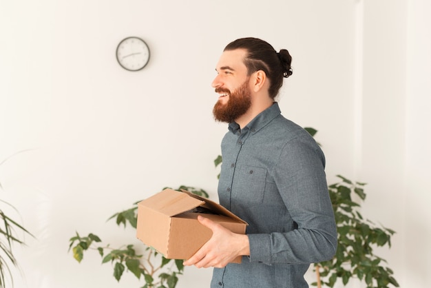 Foto di giovane uomo sorridente che si trasferisce in un altro ufficio o lavoro