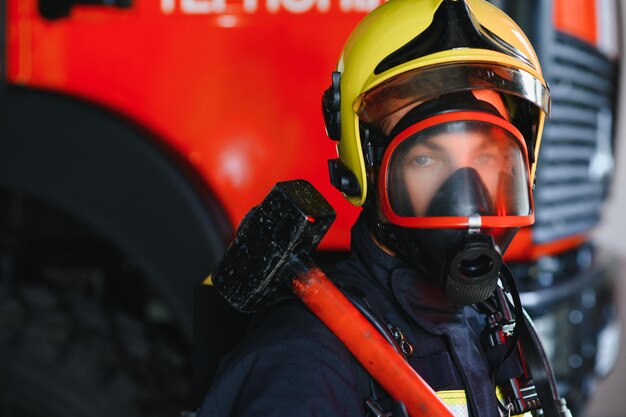 Foto di giovane vigile del fuoco con la mazza in mano vicino all'autopompa