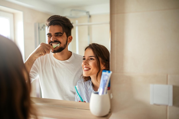 Foto di giovani coppie sorridenti che si legano mentre si lavano i denti in bagno