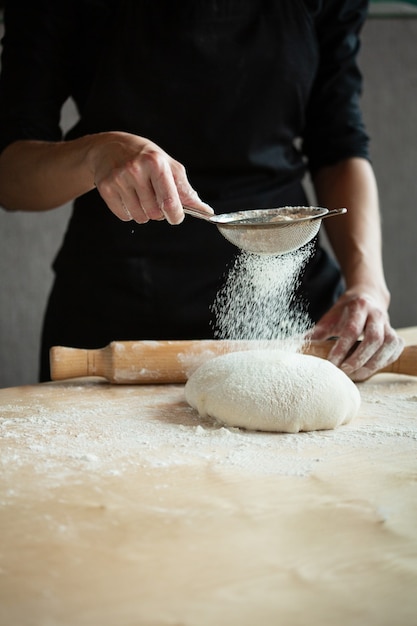Foto di mani di farina e uomini con spruzzi di farina. Cottura del pane. Impastare la pasta.