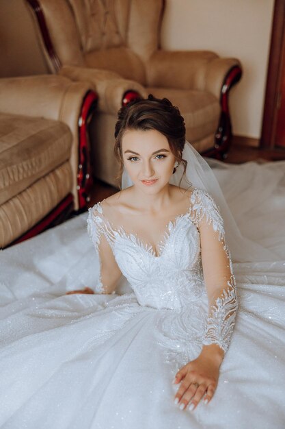 foto di moda di una bella sposa con i capelli scuri in un elegante abito da sposa e un trucco sorprendente nella stanza la mattina del matrimonio La sposa si sta preparando per il matrimonio