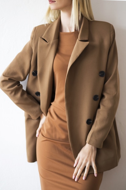 Foto di moda di una bellissima giovane donna elegante in un abito marrone e beige piuttosto oversize