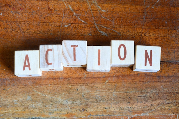 Foto di parole con oggetti di blocchi di legno disposti nella parola ACTION in inglese