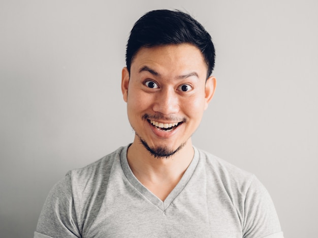 Foto di primo piano dell&#39;uomo asiatico con la faccia felice. su sfondo grigio.