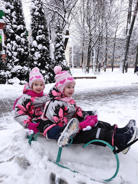 foto di ragazze gemelle su una slitta nella neve