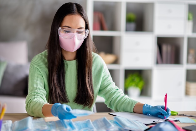 Foto di signora asiatica che lavora azienda di famiglia che organizza ordini influenza facciale raffreddore maschere mediche diffusione globale contando i clienti che preparano pacchi per la consegna stare a casa quarantena in casa