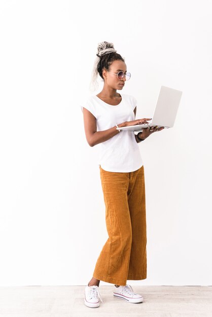 Foto di sorprendente giovane donna seria con timori in posa isolato su bianco utilizzando il computer portatile.